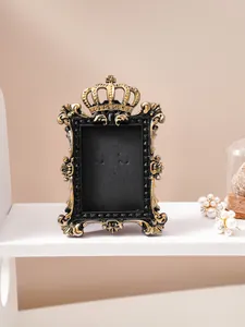 Detailed view of vintage black and gold embossed photo frame with crown ornament