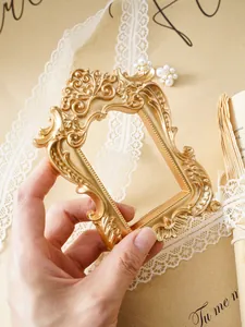 Vue détaillée d'un cadre baroque en résine dorée tenu par une main pour décoration.