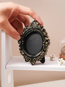 Macro view of vintage black and gold embossed frame being held by a hand on a shelf