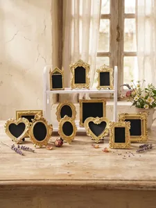Ornate vintage gold frames in various shapes displayed on a rustic wooden tabletop setting