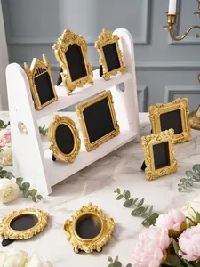 Detailed view of vintage embossed gold miniature picture frames on a white display stand.