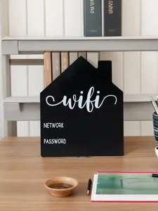 Decorative black house-shaped WiFi password sign displayed on a wooden office desk