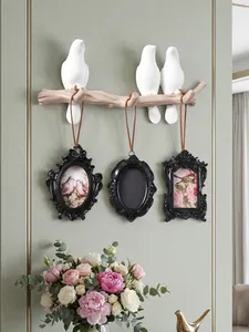 Close-up of retro black mini magnetic picture frames hanging on bird-themed wall hook