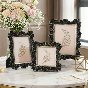 Macro view of three vintage daisy-edged black and gold frames displayed on a table