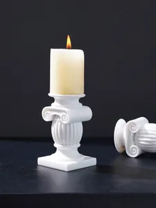 Portavelas decorativo con forma de columna jónica blanca y una vela encendida.