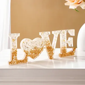 Detail van LOVE-decoratie van hars met witte stenen en gouden glitters in verloopstijl