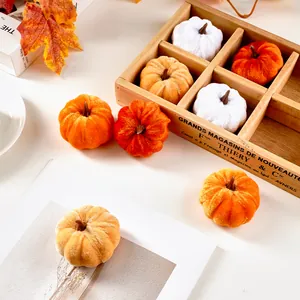 A collection of decorative velvet pumpkins in warm autumn colors within a rustic wooden tray