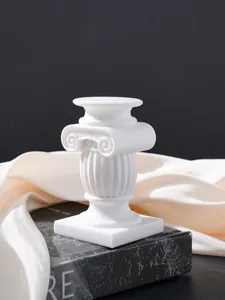 Primer plano de un candelabro de resina blanca con forma de columna romana jónica clásica