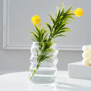 Klares Glas Raupe Vase Detailaufnahme mit welligem Design und grüner Pflanzendeko.