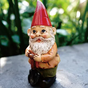 Detailed macro view of a miniature garden gnome holding a shovel in outdoor setting.