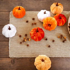 Detail of colorful velvet pumpkins and pinecones on a rustic mat for fall decor