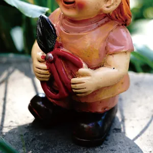 Macro detail of a decorative garden gnome statue holding red shears in an outdoor setting