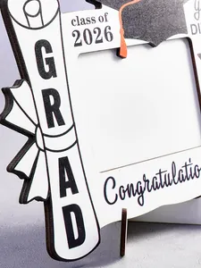 Dettaglio ravvicinato dei motivi 'Class of 2026' e 'GRAD' su cornice in legno per laurea