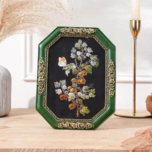 Detail view of retro octagonal green frame with golden floral carvings and botanical print