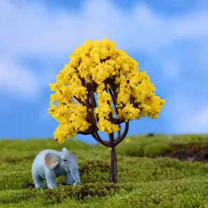 Macro view showing a miniature yellow flowering tree and small elephant figurine