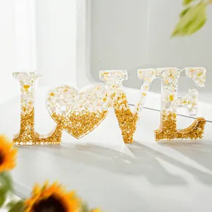 Gedetailleerde weergave van resin LOVE-ornament met goudfolie en wit kiezelsteenverloop