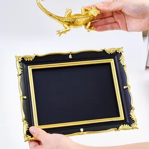 Detail of a DIY vintage black and gold photo frame with a separate gold lizard ornament