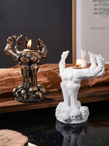 Gedetailleerd zicht op Halloween hars skelet hand kandelaars in brons en wit design