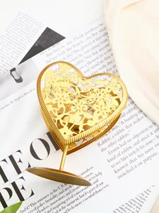 Détail d'un bougeoir doré en forme de cœur avec des motifs ajourés sur un magazine.