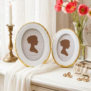 Cadres photo ovales vintage blanc et or exposés avec élégance dans un décor de table romantique.