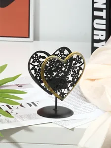 Gros plan d'un bougeoir en fer en forme de cœur avec motif ajouré pour dîners romantiques
