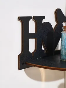 Detailed close-up of a creative black wooden wall shelf with HOME and bird design