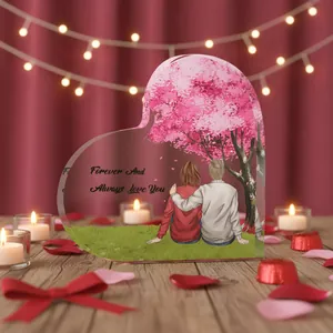 Heart-shaped acrylic anniversary gift plaque featuring a romantic couple under cherry blossoms
