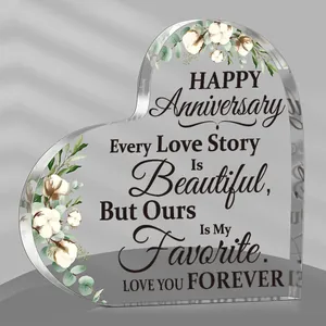 Macro view of heart-shaped acrylic plaque with anniversary message and cotton floral