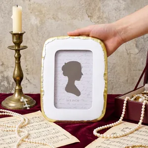 Élégant cadre photo ovale blanc et or tenu à la main dans un décor vintage raffiné