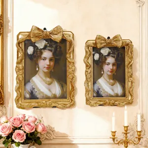 Nahaufnahme goldener Bilderrahmen mit Schleifen in klassischer Einrichtung mit Rosen.