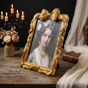 Eleganter goldener Bilderrahmen im Vintage-Stil mit 3D-Schleife auf rustikalem Tisch