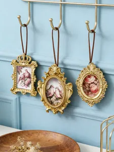 Dettaglio di tre mini cornici per foto dorate vintage appese a una parete blu decorata