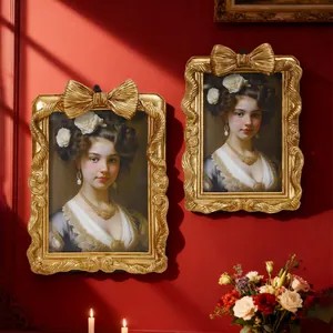 Goldene Vintage-Bilderrahmen mit Schleifendekor an einer klassischen roten Wand inszeniert