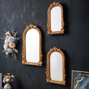 Detail von französischen, goldenen Wandspiegeln mit verzierten Rahmen auf dunkler Wand