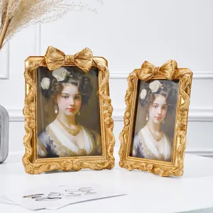 Zwei goldene Vintage-Bilderrahmen mit Schleifenakzenten auf einem weißen Tisch
