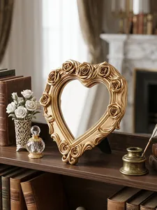 Eleganter herzförmiger Kosmetikspiegel mit goldener Rosenprägung auf einem Tisch