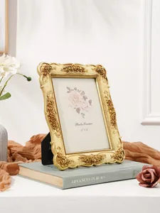Elegant ornate gold photo frame with rose carvings displayed on a decorative book prop