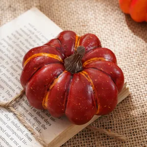 Primo piano di una zucca decorativa rossa con strisce gialle su un vecchio libro vintage