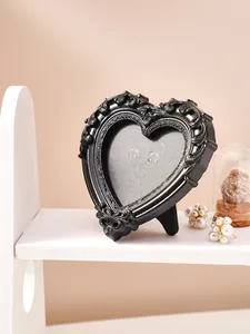 Primer plano de un marco de fotos vintage negro en forma de corazón con tallas florales