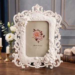 Primer plano de un marco de fotos vintage de resina blanca con relieves de rosas