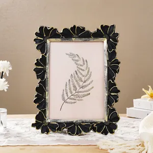 Close-up of vintage black and gold daisy floral photo frame on a lace tablecloth