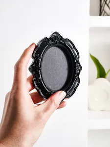 Close-up of a mini vintage black ornate oval frame held in hand for creative photos