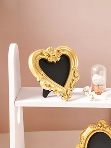 Elegant vintage ornate gold heart-shaped embossed picture frame displayed on a white shelf