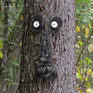 Detailed macro view of quirky tree face resin ornaments on a rustic garden tree trunk