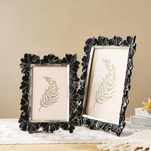 Detailed view of two vintage black and gold floral photo frames on a lace cloth