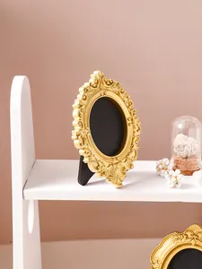 Close-up view of a vintage golden ornate oval frame with relief carvings on a shelf.