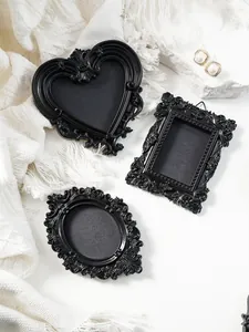 Macro view of three vintage black magnetic miniature photo frames with ornate carvings.