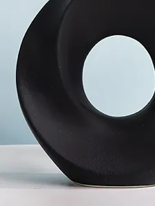 Detaillierte Nahaufnahme der mattschwarzen, körnigen Textur einer kreativen Donut-Vase.