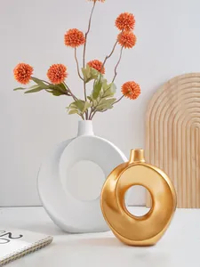 Detail von minimalistischen Donut-Ring-Harzvasen in Weiß und Gold mit Blumen