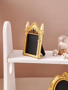 Close-up view of a vintage gold gothic arch photo frame displayed on a white shelf